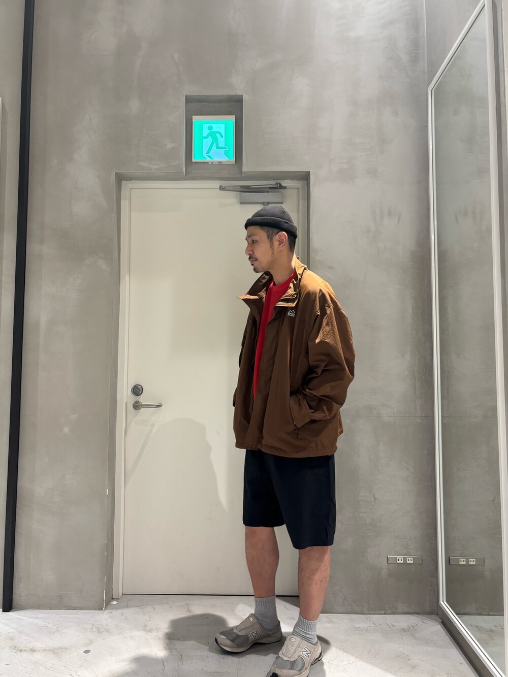 ブラウン系のナイロンジャケット、レッド系のTシャツ/カットソー、ブラック系のその他パンツを着用したメンズの春コーディネートの2枚目の写真