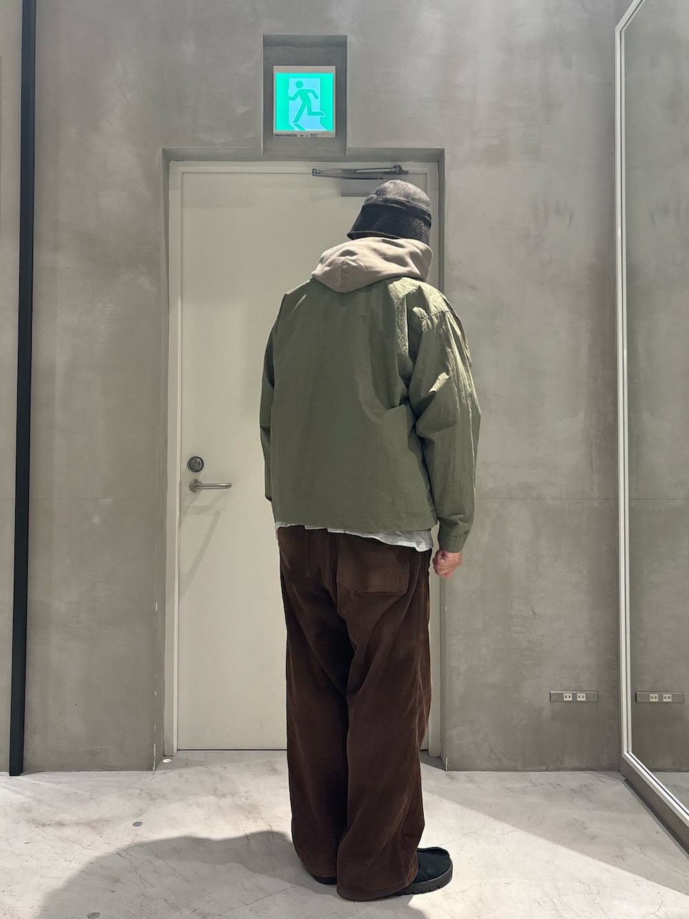グリーン系のナイロンジャケット、ベージュ系のパーカーを着用したメンズの冬コーディネートの2枚目の写真