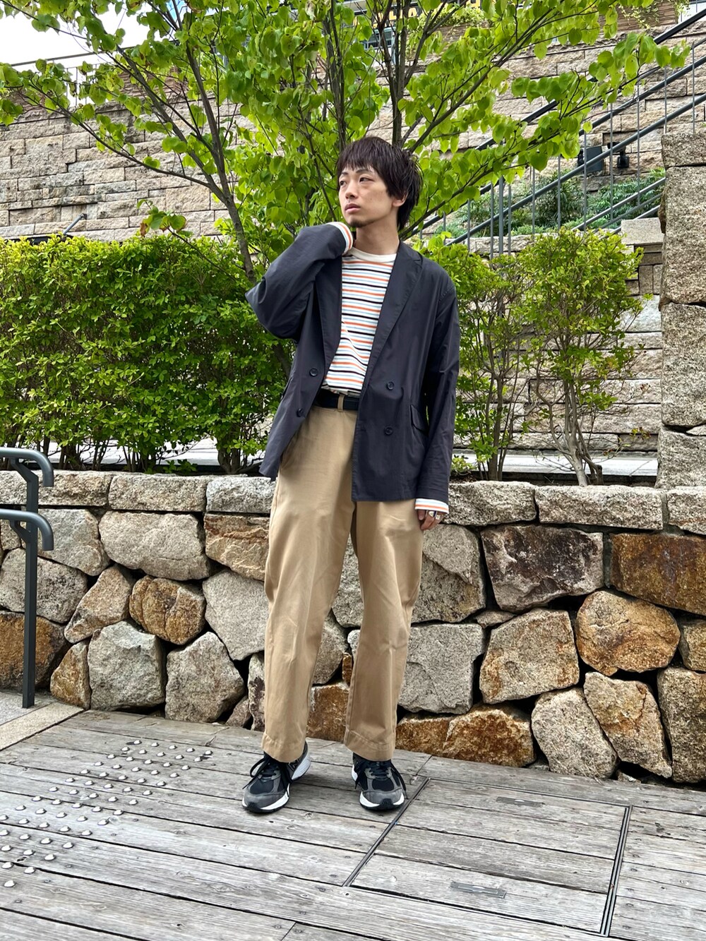 ブラック系のテーラードジャケット、ホワイト系のTシャツ/カットソー、ベージュ系のチノパンツを着用したメンズの秋コーディネートの2枚目の写真