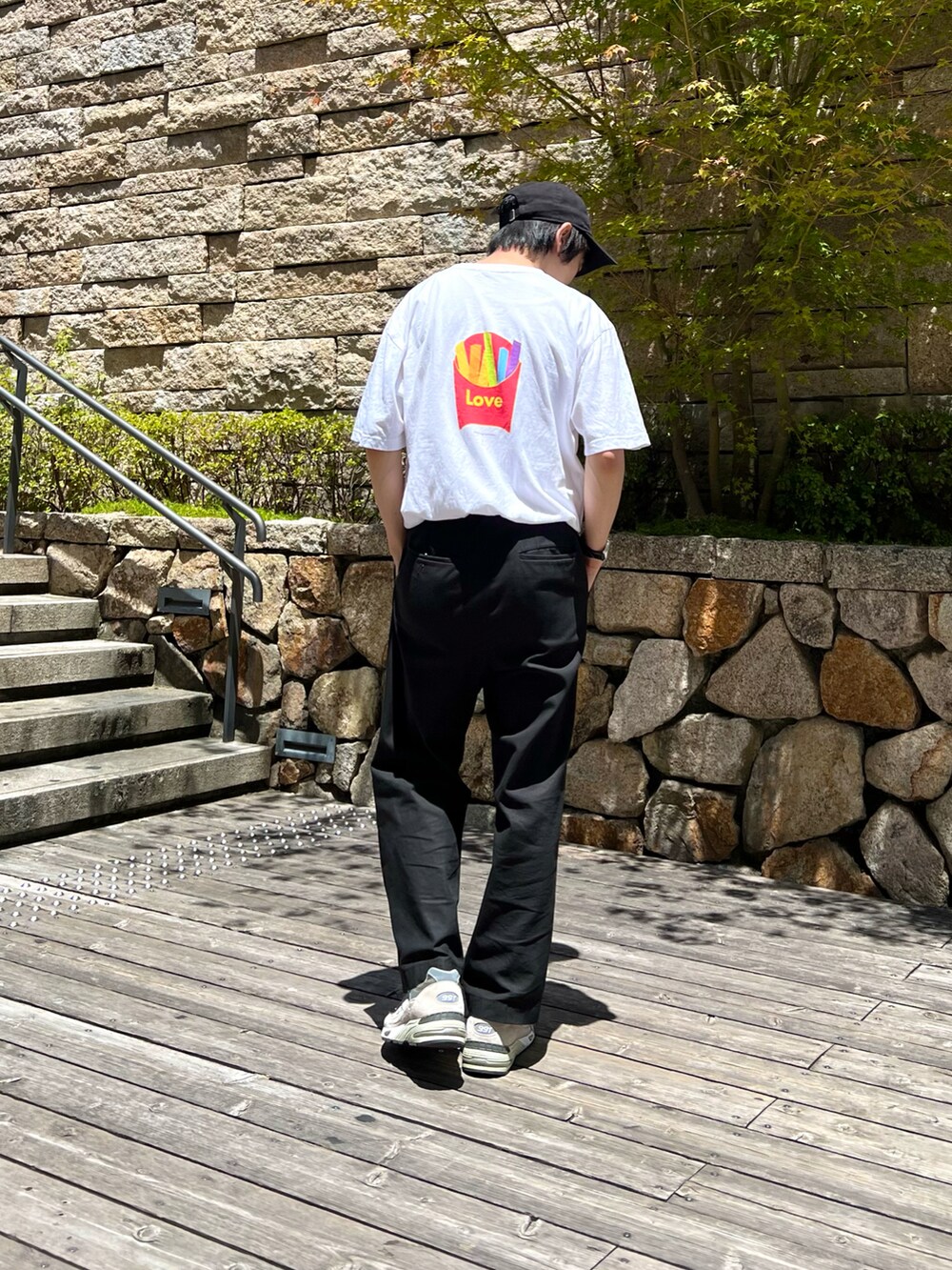 ホワイト系のTシャツ/カットソー、ブラック系のスラックス、グレー系のスニーカーを着用したメンズの夏コーディネートの2枚目の写真