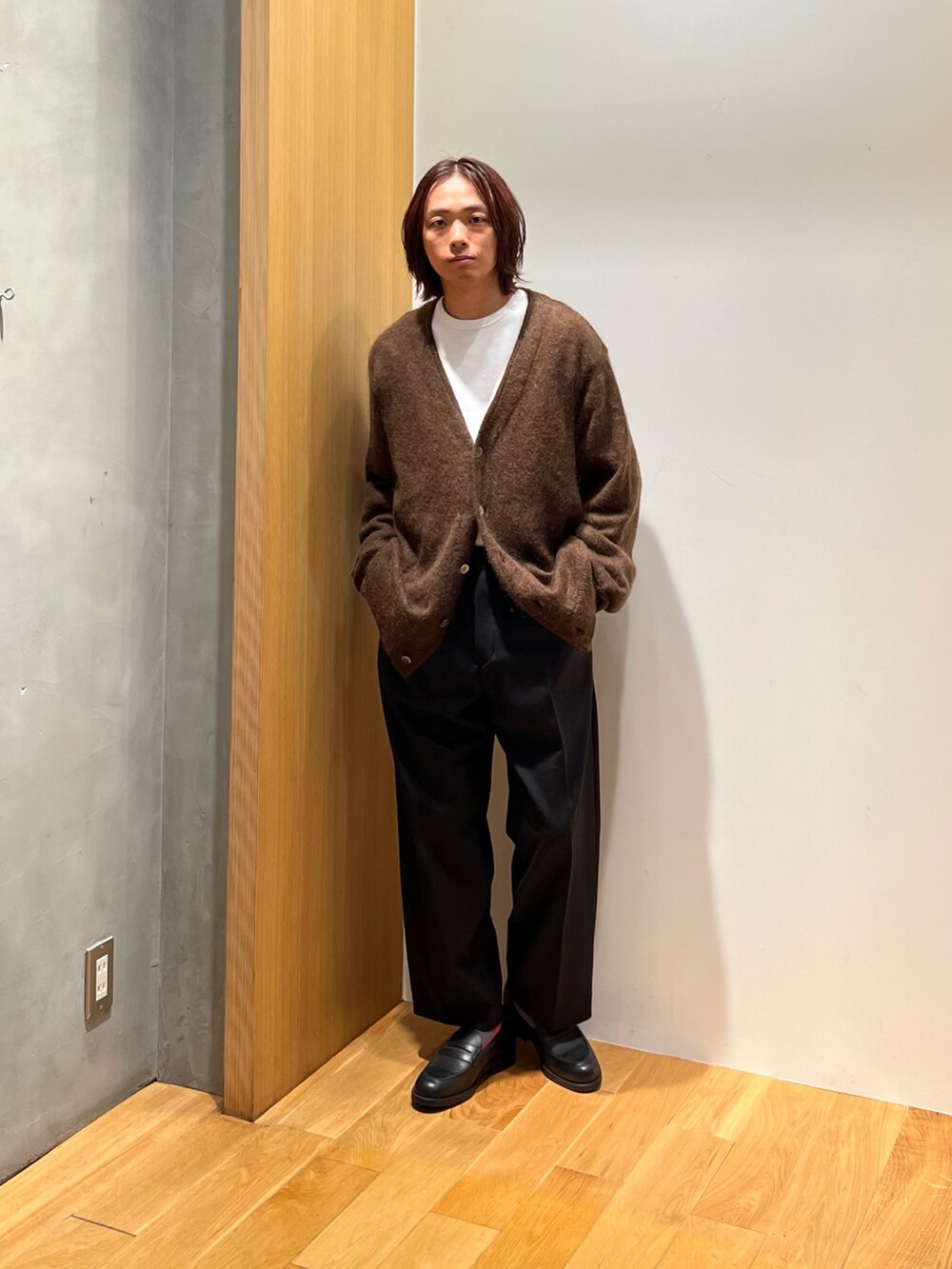 ブラウン系のカーディガン/ボレロ、ベージュ系のTシャツ/カットソー、ブラック系のスラックスを着用したメンズの秋コーディネートの3枚目の写真