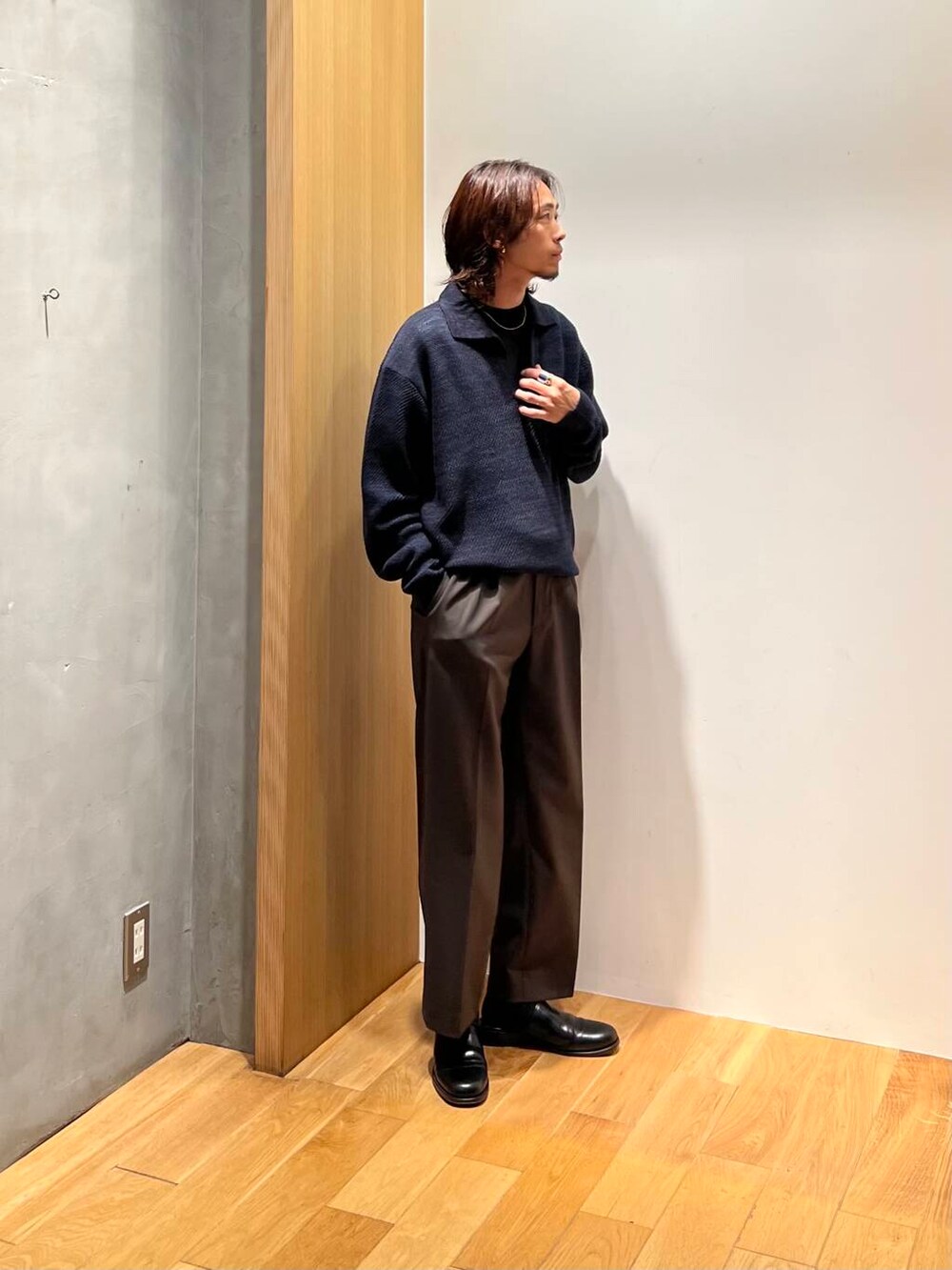 ブラック系のTシャツ/カットソー、ブルー系のニット/セーター、ブラウン系のスラックスを着用したメンズの秋コーディネートの5枚目の写真