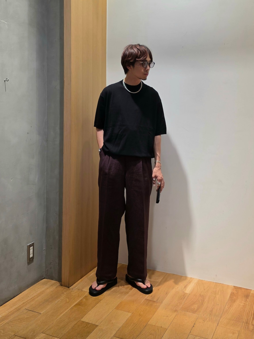 ブラック系のニット/セーター、ブラウン系のその他パンツ、ブラック系の名刺入れを着用したメンズの夏コーディネートの3枚目の写真