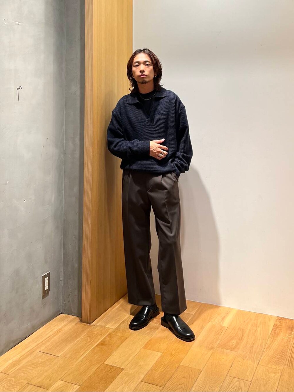 ブラック系のTシャツ/カットソー、ブルー系のニット/セーター、ブラウン系のスラックスを着用したメンズの秋コーディネートの3枚目の写真