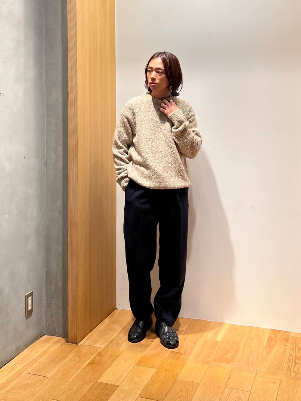 ブラック系のサンダル、ベージュ系のニット/セーター、ブルー系のスラックスを着用したメンズの秋コーディネートの3枚目の写真