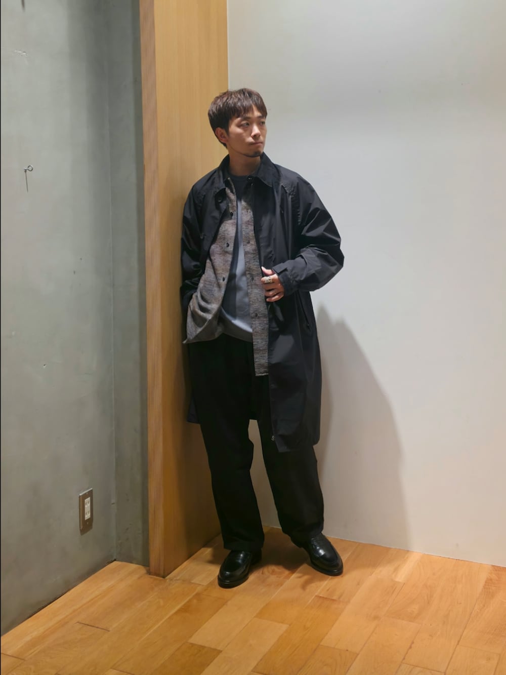 ブラック系のステンカラーコート、グレー系のシャツ/ブラウス、グレー系のTシャツ/カットソーを着用したメンズの秋コーディネートの2枚目の写真