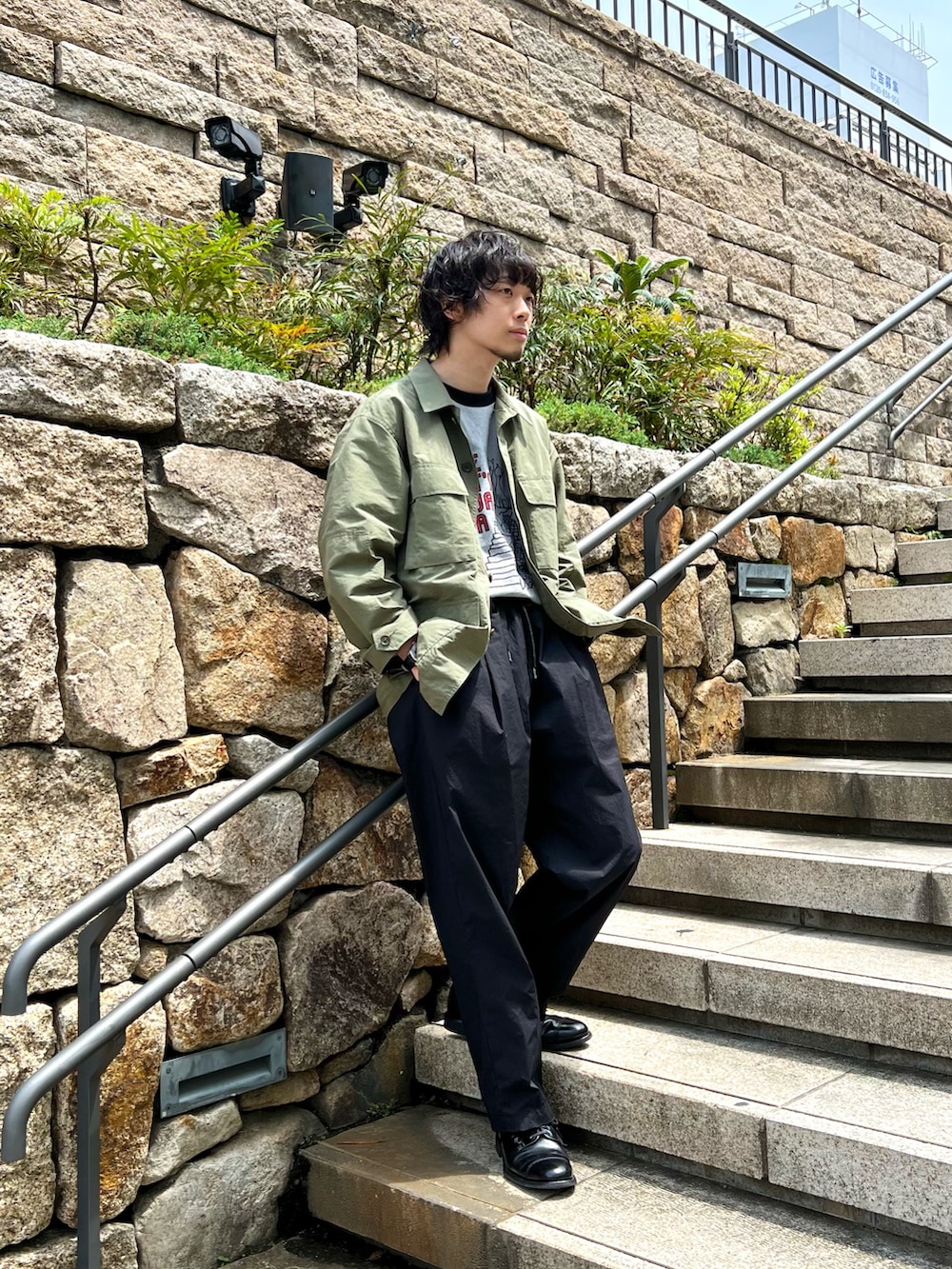 グレー系のTシャツ/カットソー、グリーン系のミリタリージャケット、ブラック系のその他パンツを着用したメンズの春コーディネートの2枚目の写真
