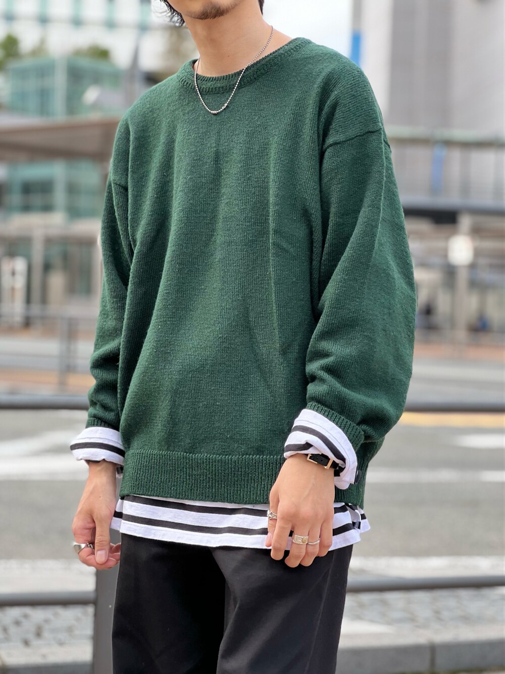 グリーン系のニット/セーター、ブラック系のTシャツ/カットソー、ブラック系のスラックスを着用したメンズの秋コーディネートの3枚目の写真