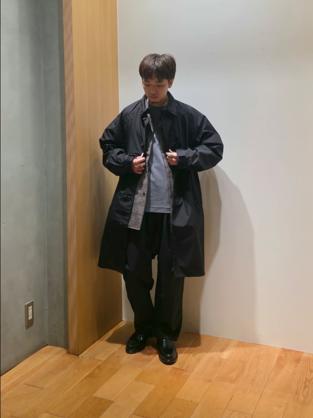 ブラック系のステンカラーコート、グレー系のシャツ/ブラウス、グレー系のTシャツ/カットソーを着用したメンズの秋コーディネートの5枚目の写真