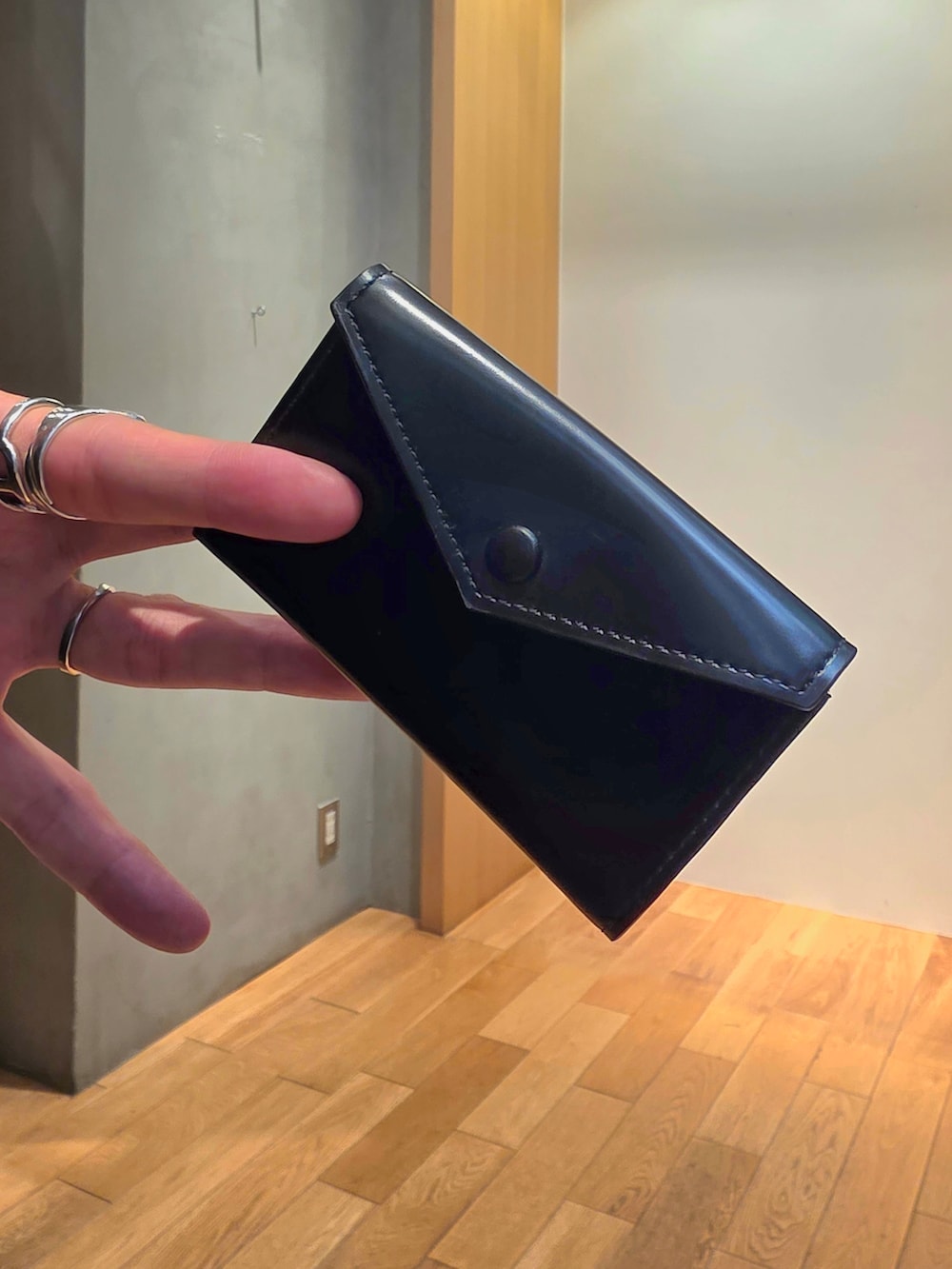 ブラック系のニット/セーター、ブラウン系のその他パンツ、ブラック系の名刺入れを着用したメンズの夏コーディネートの4枚目の写真