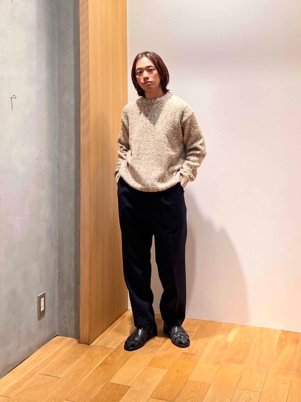 ブラック系のサンダル、ベージュ系のニット/セーター、ブルー系のスラックスを着用したメンズの秋コーディネートの4枚目の写真