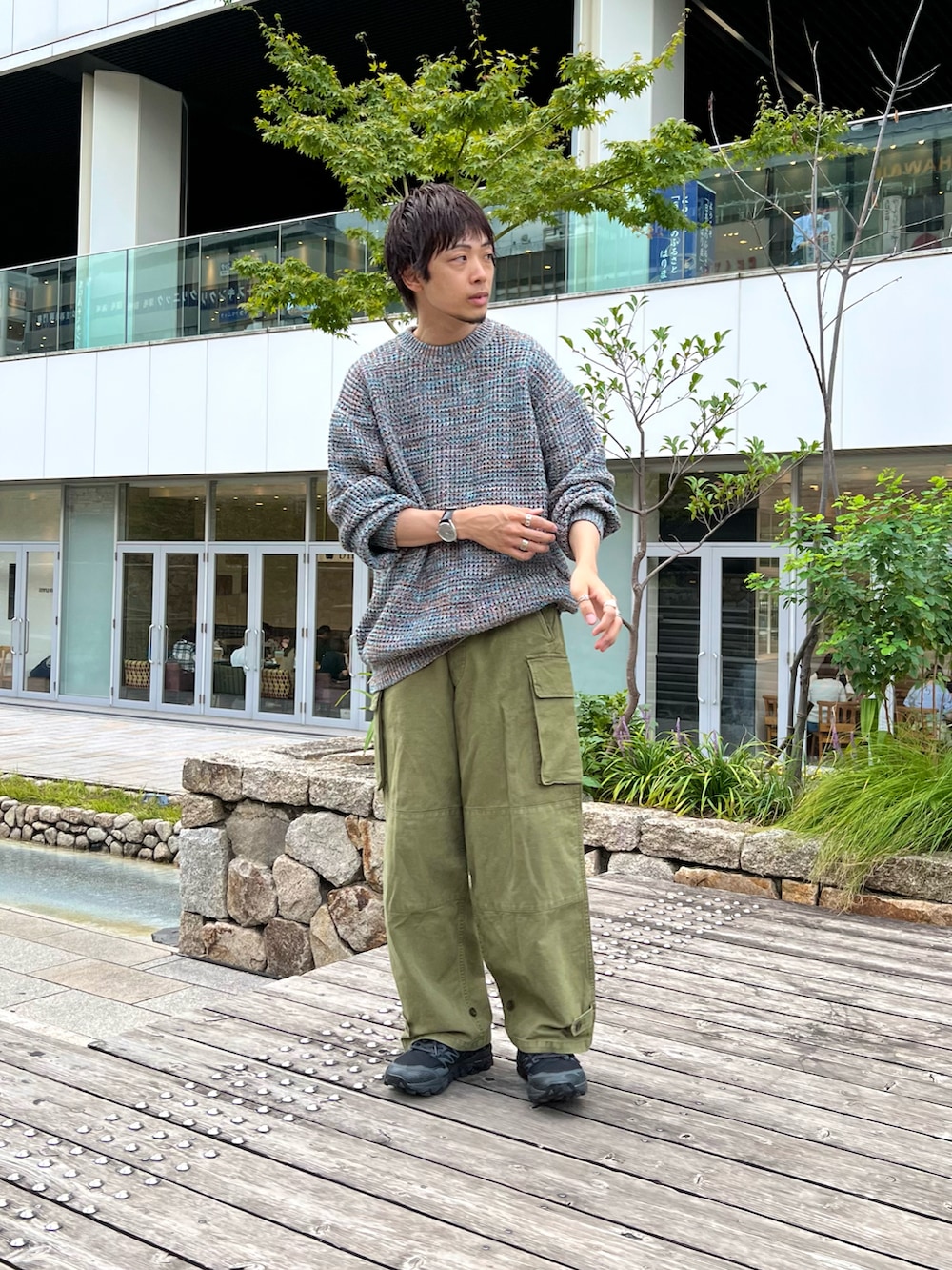 ブルー系のニット/セーター、グリーン系のカーゴパンツ、ブラック系のスニーカーを着用したメンズの秋コーディネートの2枚目の写真