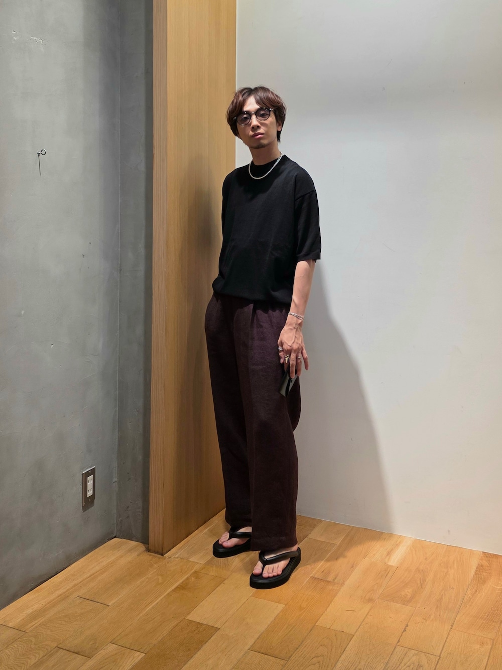 ブラック系のニット/セーター、ブラウン系のその他パンツ、ブラック系の名刺入れを着用したメンズの夏コーディネートの2枚目の写真