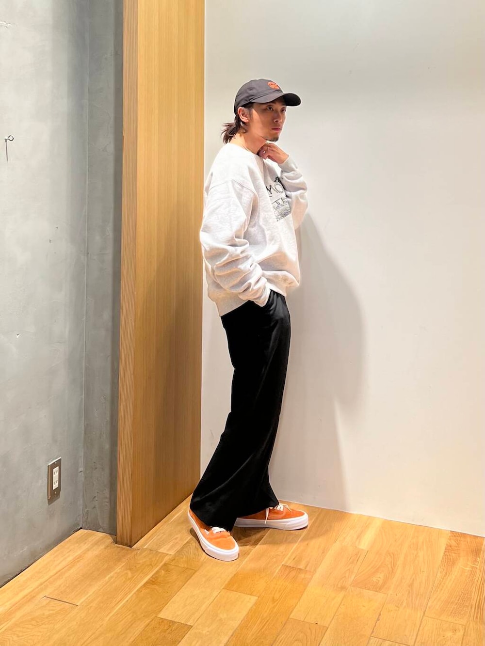 オレンジ系のスニーカー、ブラック系のスラックス、グレー系のスウェットを着用したメンズの秋コーディネートの3枚目の写真