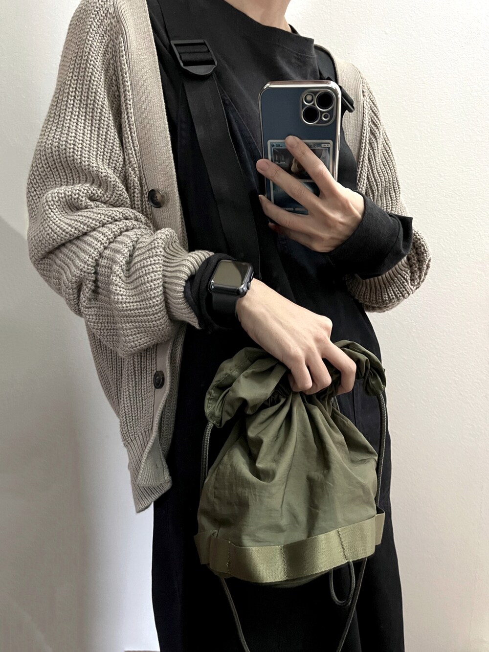 グリーン系のショルダーバッグ、ベージュ系のカーディガン/ボレロ、ブラック系のTシャツ/カットソーを着用したレディースの冬コーディネートの2枚目の写真