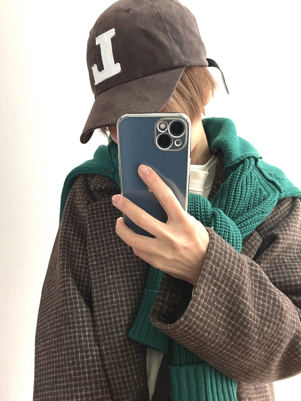 ブラウン系のピーコート、グリーン系のニット/セーター、ブラウン系のキャップを着用したレディースの冬コーディネートの2枚目の写真