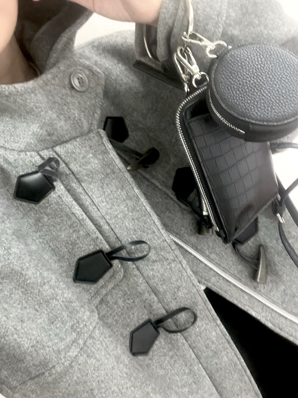 グレー系のダッフルコート、ブラック系のTシャツ/カットソー、ブラック系のスラックスを着用したレディースの冬コーディネートの2枚目の写真