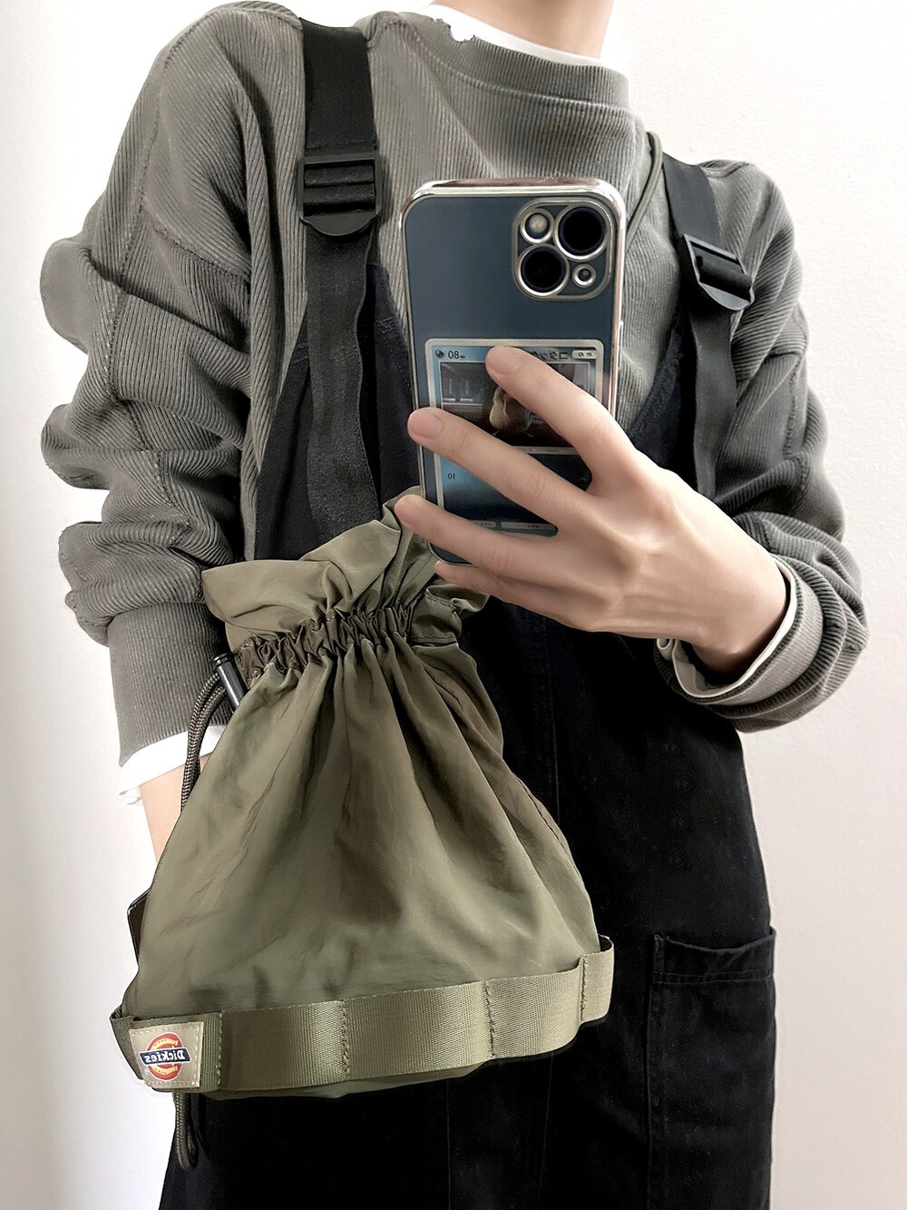 グレー系のスウェット、グリーン系のショルダーバッグを着用したレディースの冬コーディネートの2枚目の写真