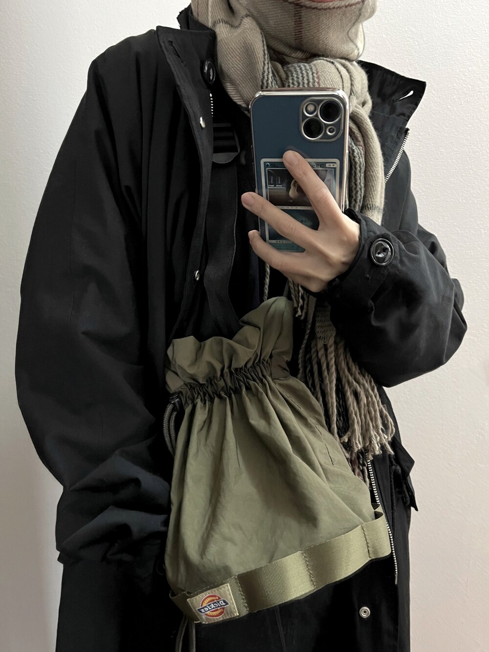 グリーン系のショルダーバッグ、ベージュ系のカーディガン/ボレロ、ブラック系のTシャツ/カットソーを着用したレディースの冬コーディネートの4枚目の写真