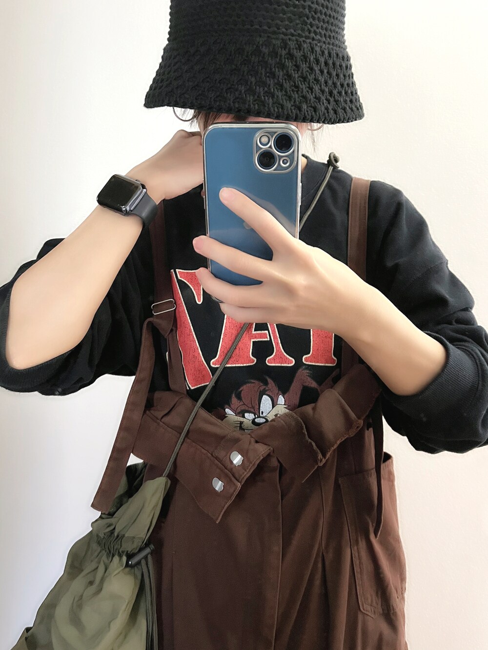 ブラウン系のジャンパースカート、グリーン系のショルダーバッグ、ブラック系のスウェットを着用したレディースの春コーディネートの2枚目の写真