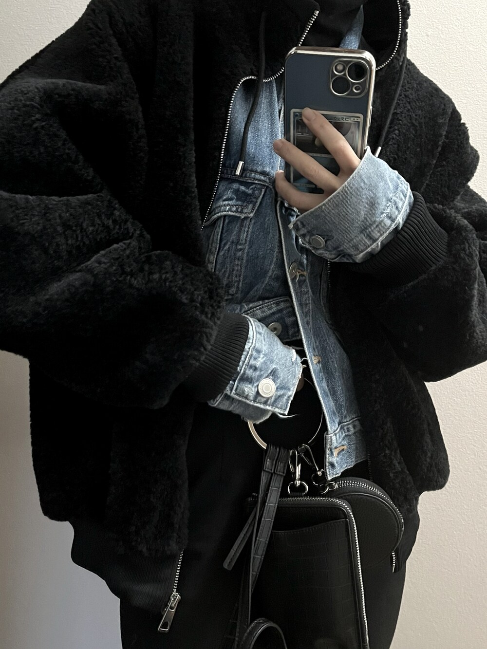 ブラック系のムートンコート、ブルー系のデニムジャケットを着用したレディースの冬コーディネートの2枚目の写真