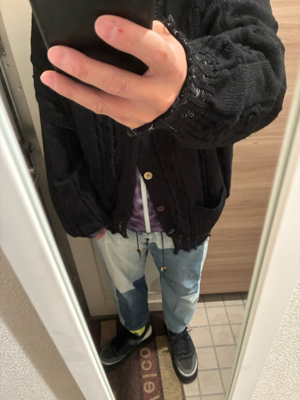 ブラック系のトレンチコート、ブルー系のデニムパンツ、ブラック系のスニーカーを着用したメンズの冬コーディネートの2枚目の写真