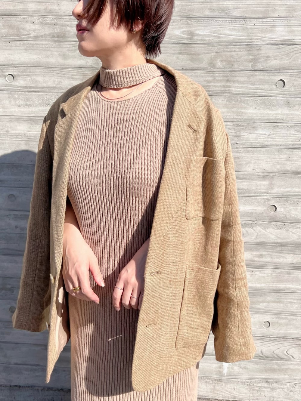 ベージュ系のテーラードジャケット、ベージュ系のワンピース、ブラック系のスリッポンを着用したレディースの春コーディネートの2枚目の写真