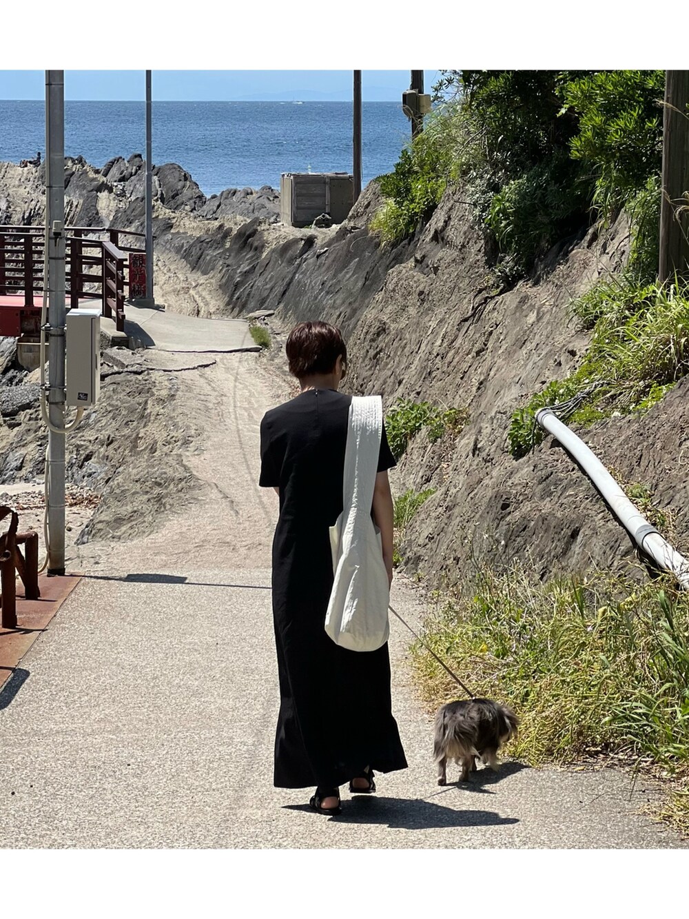 ブラック系のワンピース、ホワイト系のショルダーバッグを着用したレディースの夏コーディネートの2枚目の写真