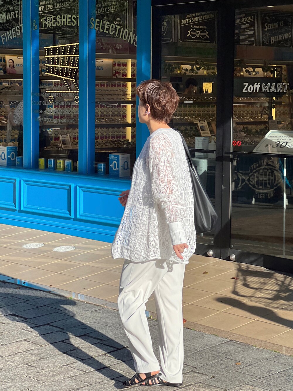 ブラック系のサンダル、ホワイト系のシャツ/ブラウス、ホワイト系のパンツを着用したレディースの秋コーディネートの2枚目の写真