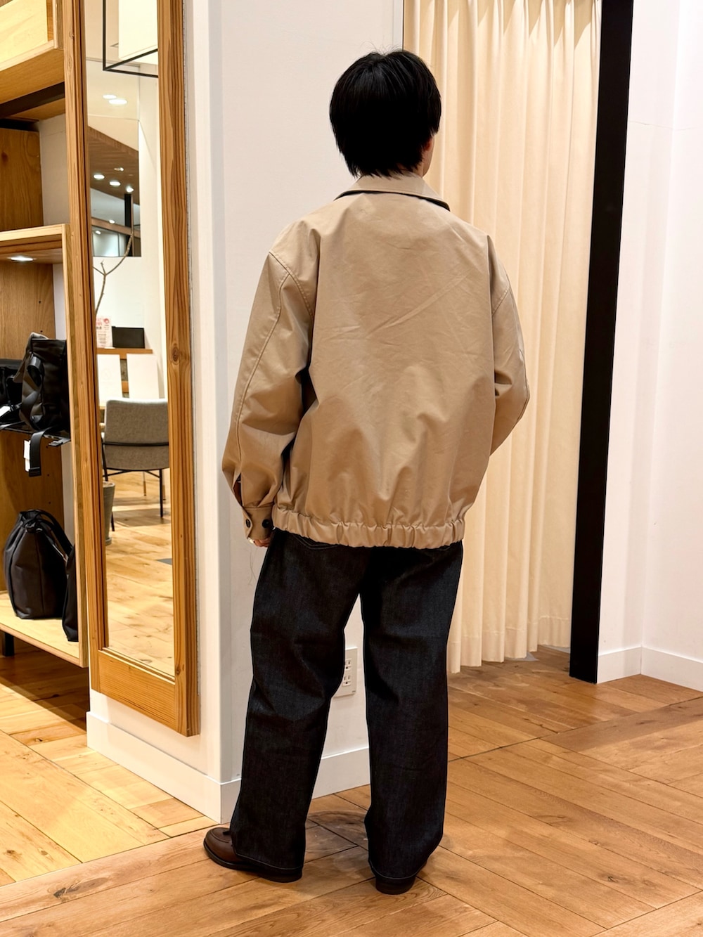 ベージュ系のブルゾン、ブルー系のデニムパンツ、ブラウン系のドレスシューズを着用したメンズの冬コーディネートの3枚目の写真