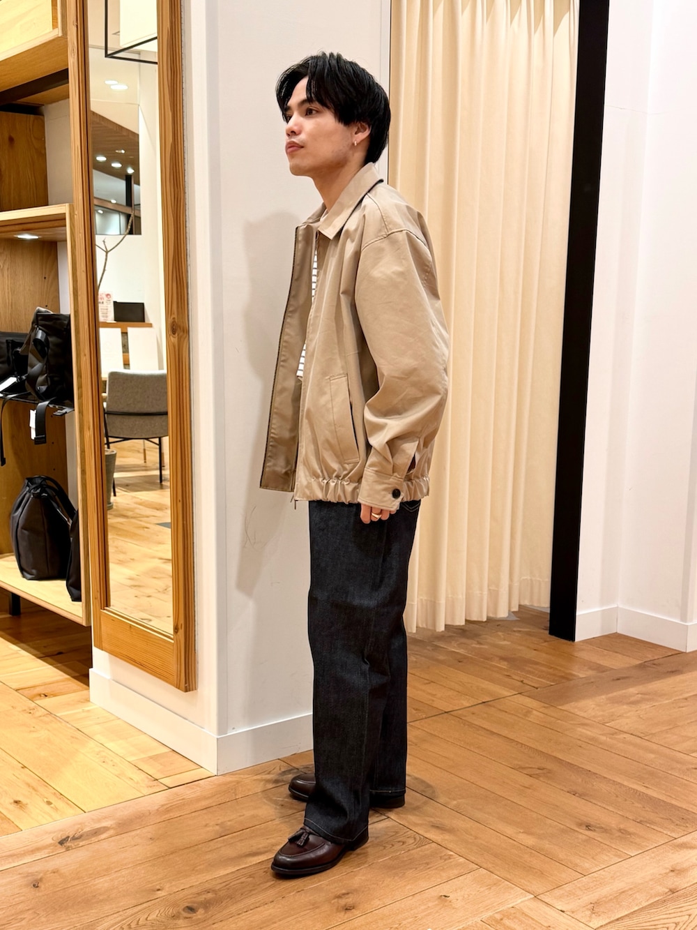 ベージュ系のブルゾン、ブルー系のデニムパンツ、ブラウン系のドレスシューズを着用したメンズの冬コーディネートの2枚目の写真