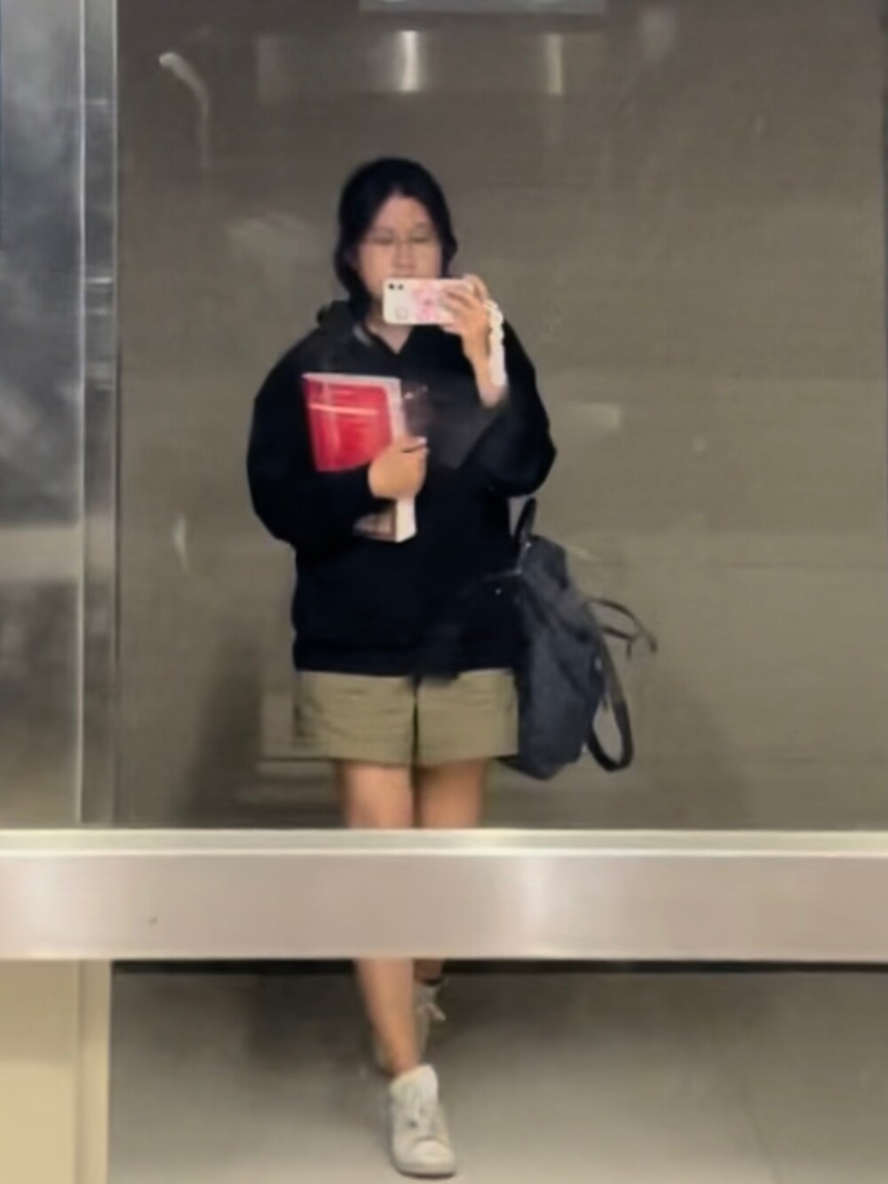 ブラック系のパーカー、グレー系のショルダーバッグ、ベージュ系のカーゴパンツを着用したレディースの夏コーディネートの2枚目の写真