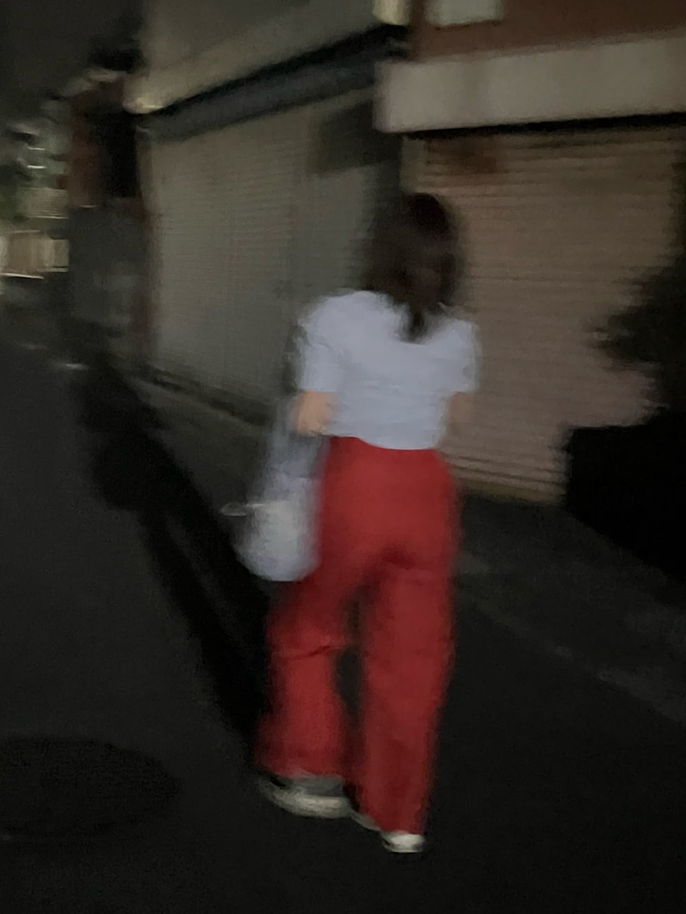 レッド系のスラックス、ブラック系のスニーカー、ブルー系のハンドバッグを着用したレディースの秋コーディネートの2枚目の写真