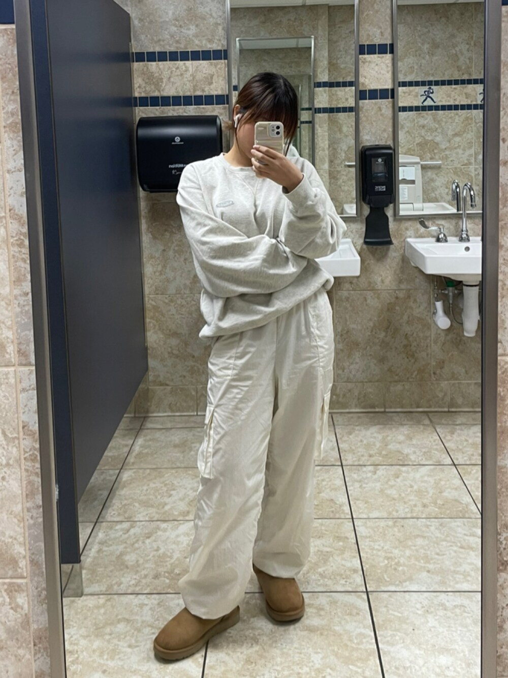 ベージュ系のスウェット、ホワイト系のパンツ、ブラウン系のブーツを着用したレディースの秋コーディネートの2枚目の写真