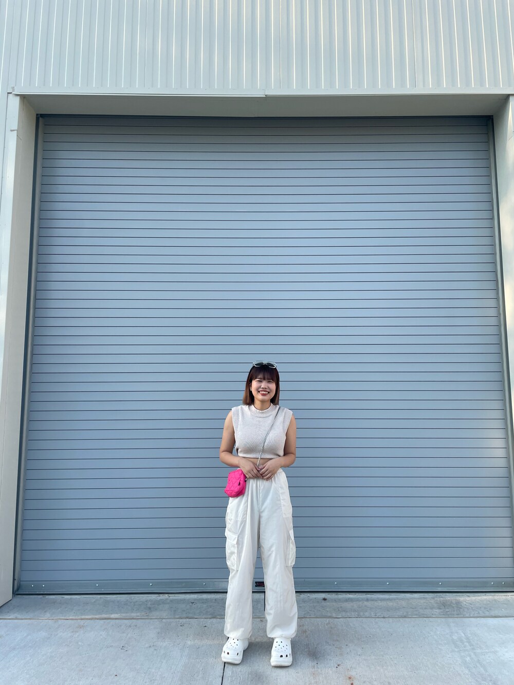 ホワイト系のパンツ、ホワイト系のサンダル、ピンク系のショルダーバッグを着用したレディースの秋コーディネートの2枚目の写真