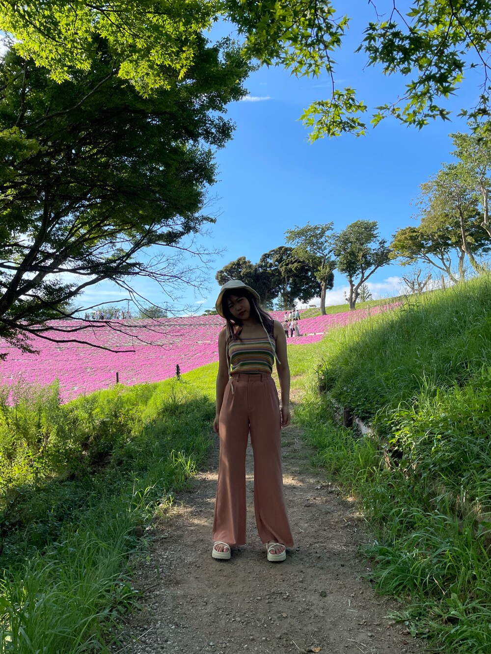 ピンク系のパンツ、ホワイト系のテーラードジャケット、ホワイト系のショルダーバッグを着用したレディースの春コーディネートの3枚目の写真