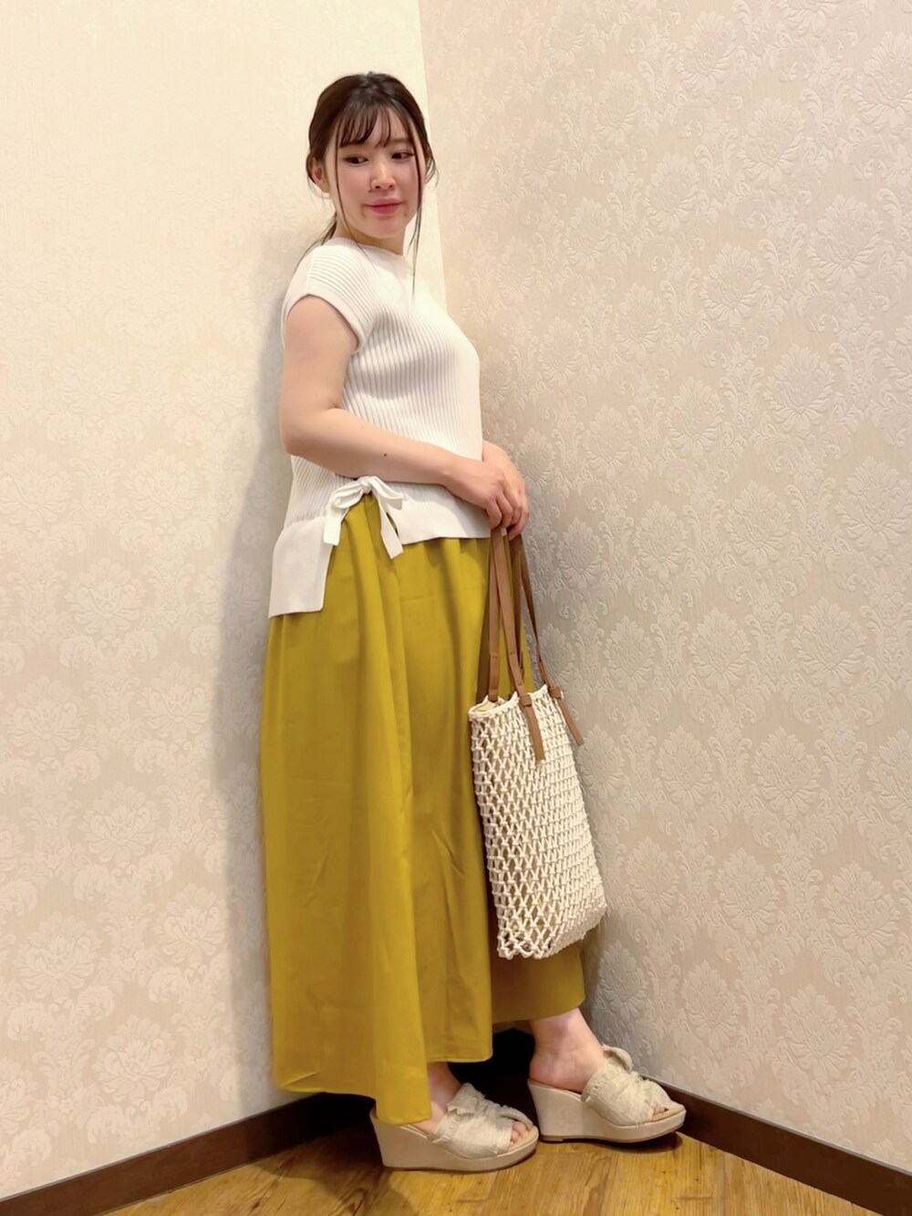 イエロー系のワンピース、ホワイト系のトートバッグ、ベージュ系のサンダルを着用したレディースの春コーディネートの2枚目の写真