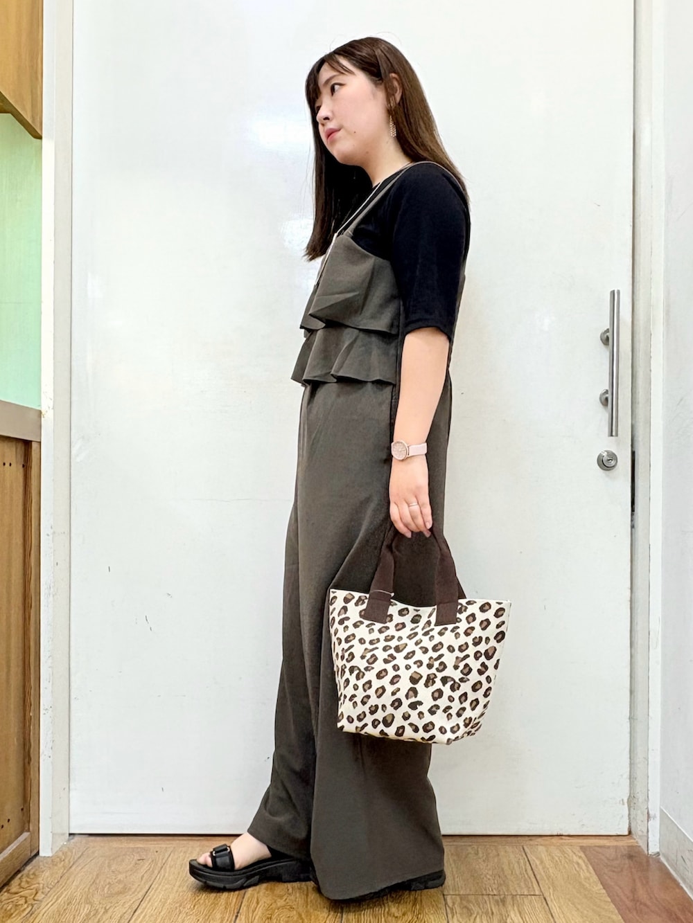 ブラック系のTシャツ/カットソー、ブラック系のサンダル、ブラウン系のサロペット/オーバーオールを着用したレディースの秋コーディネートの2枚目の写真