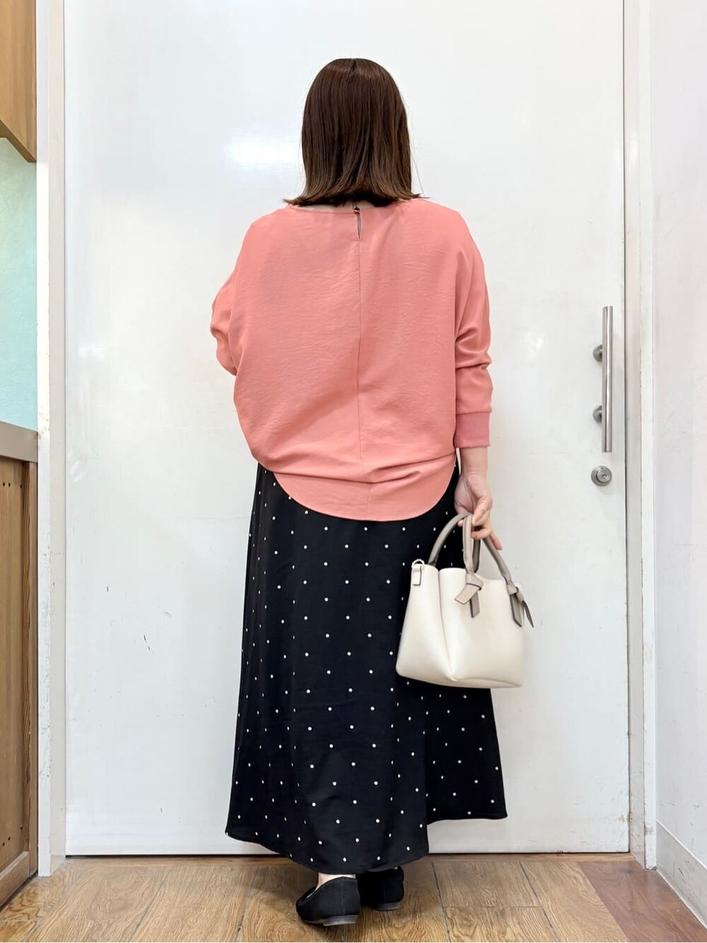 ピンク系のシャツ/ブラウス、ブラック系のスカート、ブラック系のパンプスを着用したレディースの春コーディネートの4枚目の写真