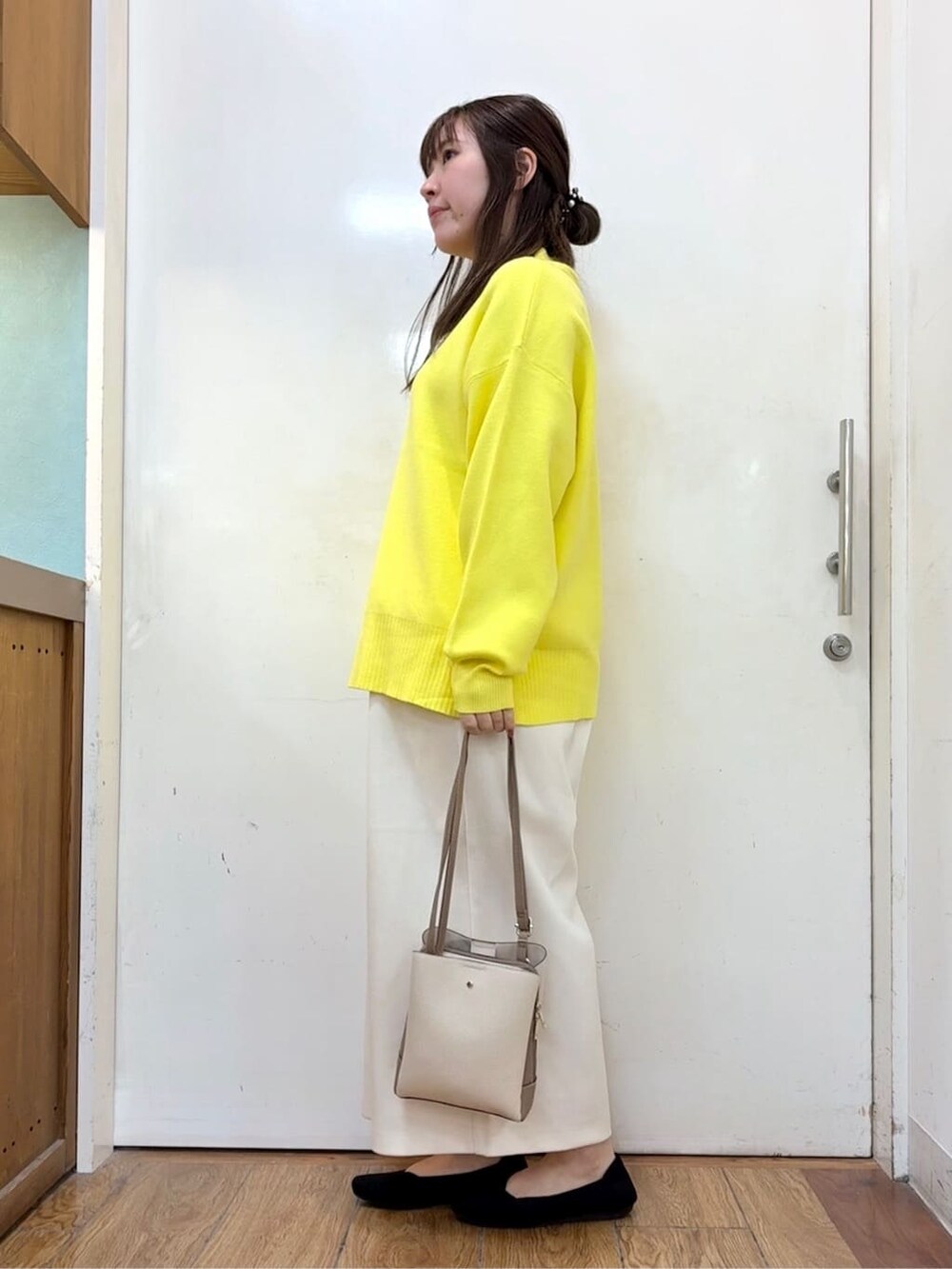 イエロー系のニット/セーター、ホワイト系のその他パンツ、ブラック系のパンプスを着用したレディースの冬コーディネートの2枚目の写真