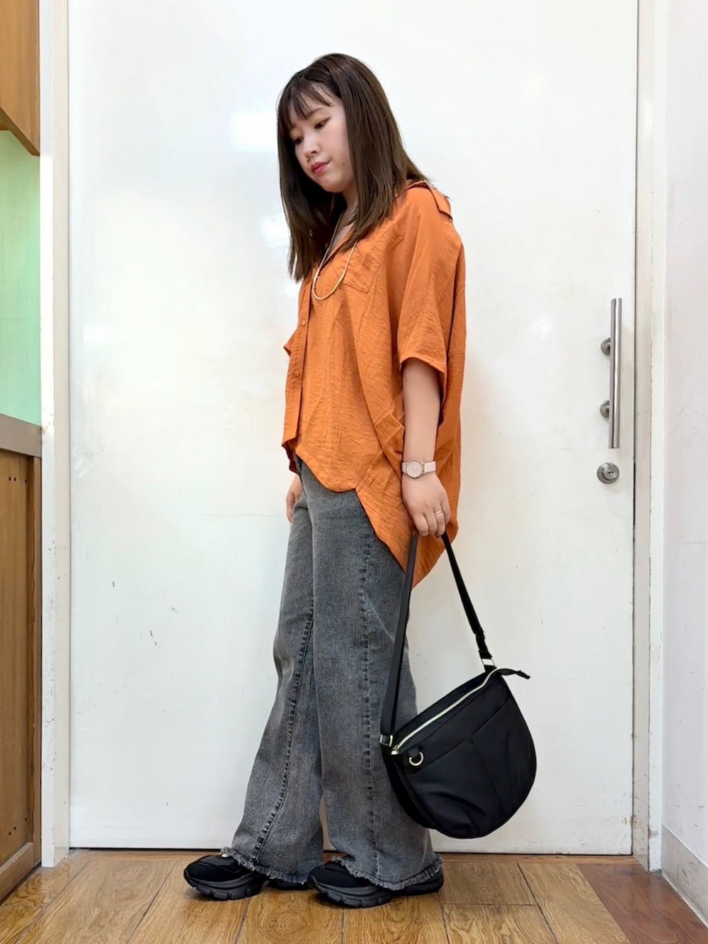 オレンジ系のシャツ/ブラウス、ブラック系のデニムパンツ、ブラック系のショルダーバッグを着用したレディースの秋コーディネートの2枚目の写真