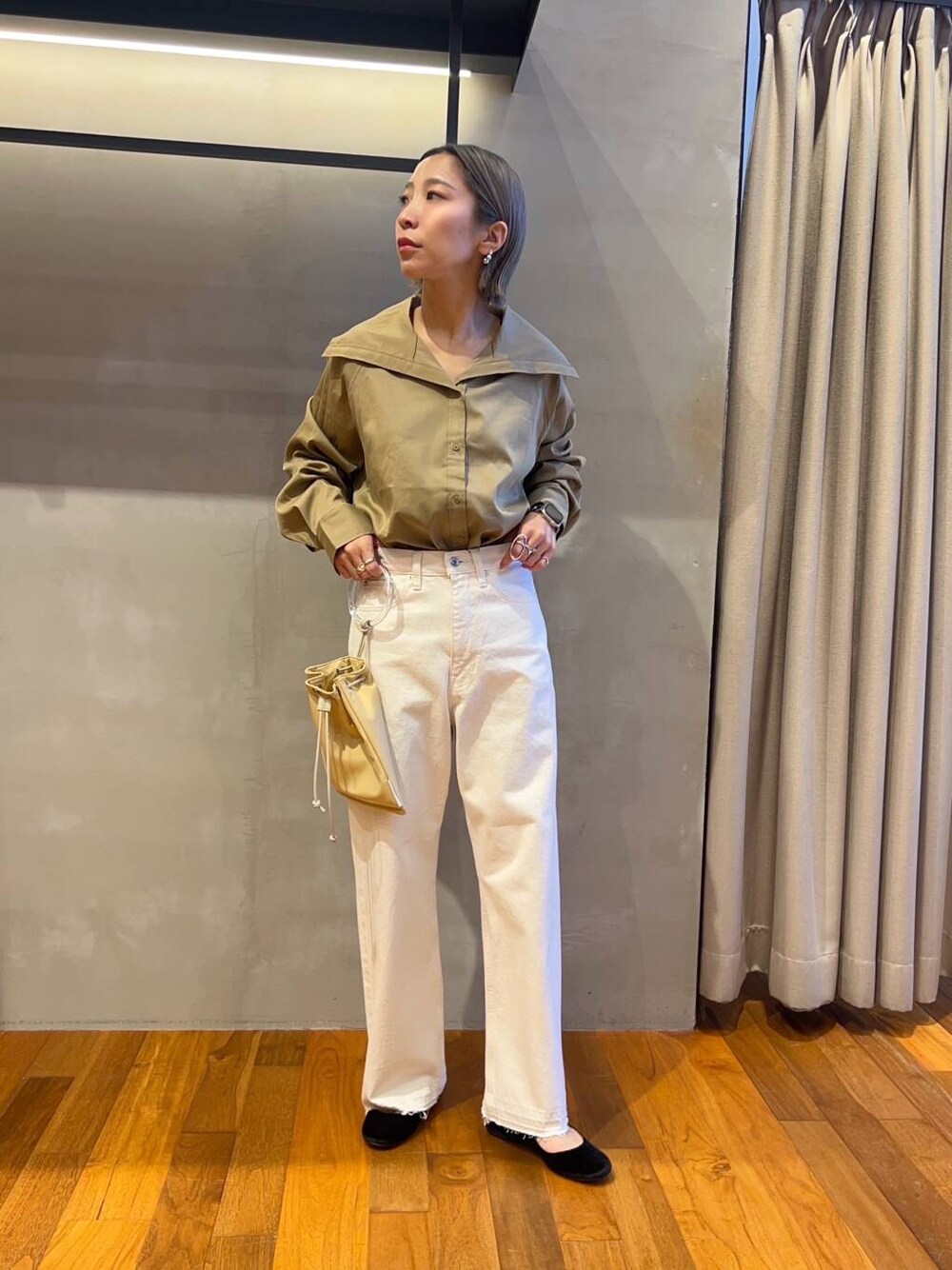 イエロー系のTシャツ/カットソー、イエロー系のショルダーバッグ、ホワイト系のデニムパンツを着用したレディースの秋コーディネートの4枚目の写真