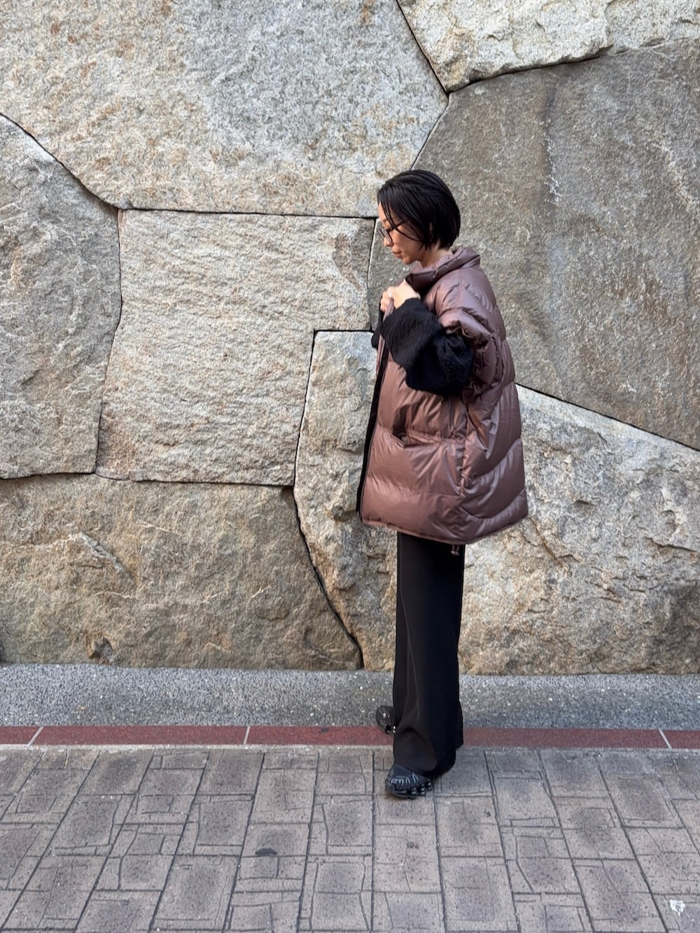 ブラック系のニット/セーター、ブラウン系のダウンベスト、ブラック系のその他パンツを着用したレディースの秋コーディネートの2枚目の写真