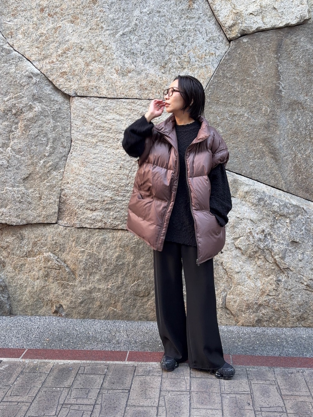 ブラック系のニット/セーター、ブラウン系のダウンベスト、ブラック系のその他パンツを着用したレディースの秋コーディネートの4枚目の写真