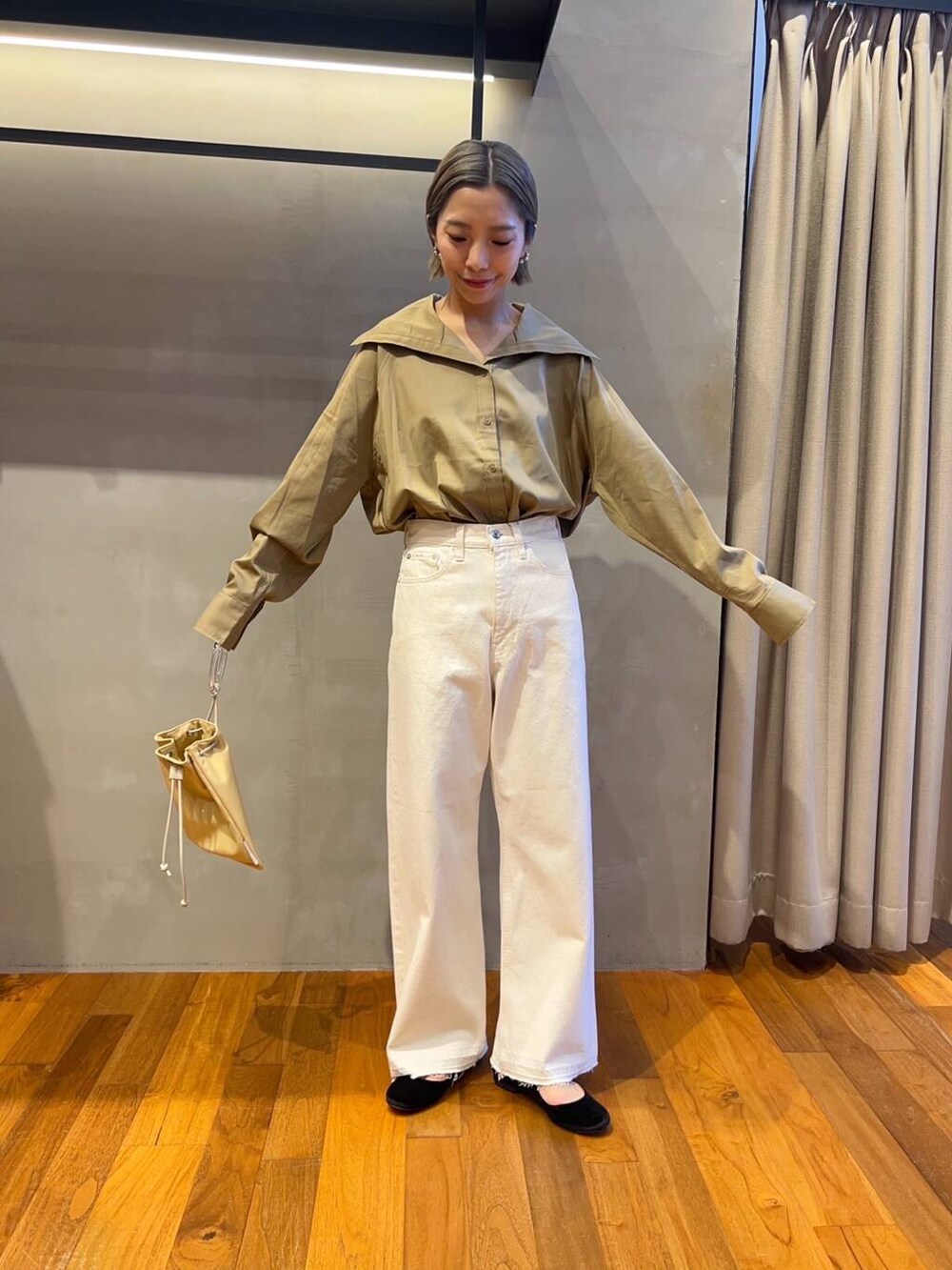 イエロー系のTシャツ/カットソー、イエロー系のショルダーバッグ、ホワイト系のデニムパンツを着用したレディースの秋コーディネートの3枚目の写真