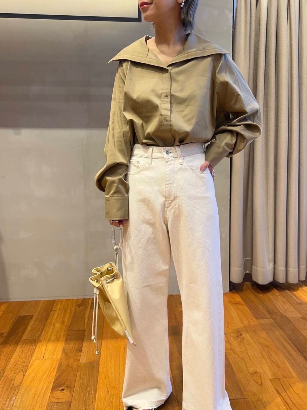 イエロー系のTシャツ/カットソー、イエロー系のショルダーバッグ、ホワイト系のデニムパンツを着用したレディースの秋コーディネートの6枚目の写真