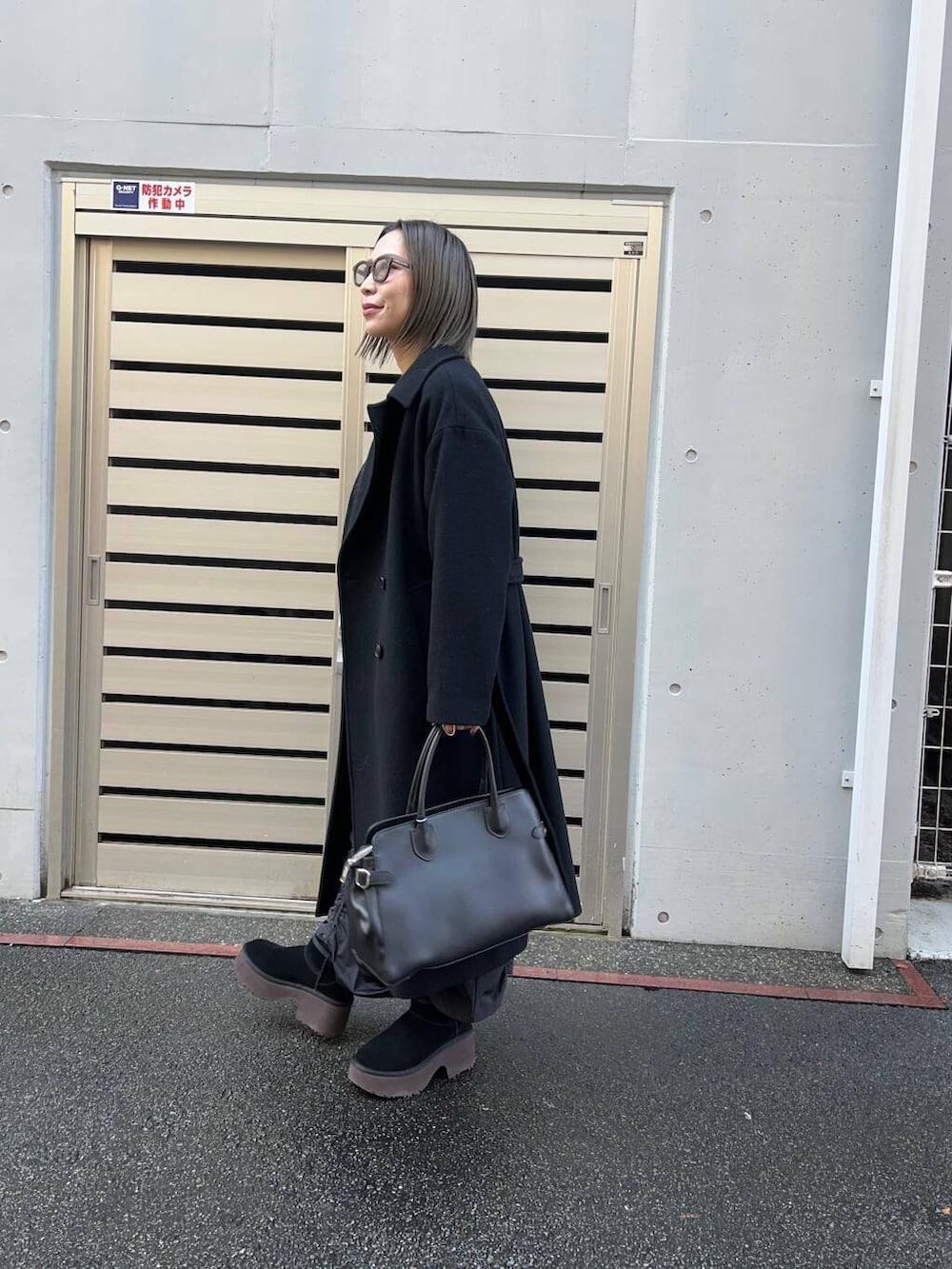 ブラック系のチェスターコート、ブラック系のスカート、グレー系のカーディガン/ボレロを着用したレディースの冬コーディネートの3枚目の写真