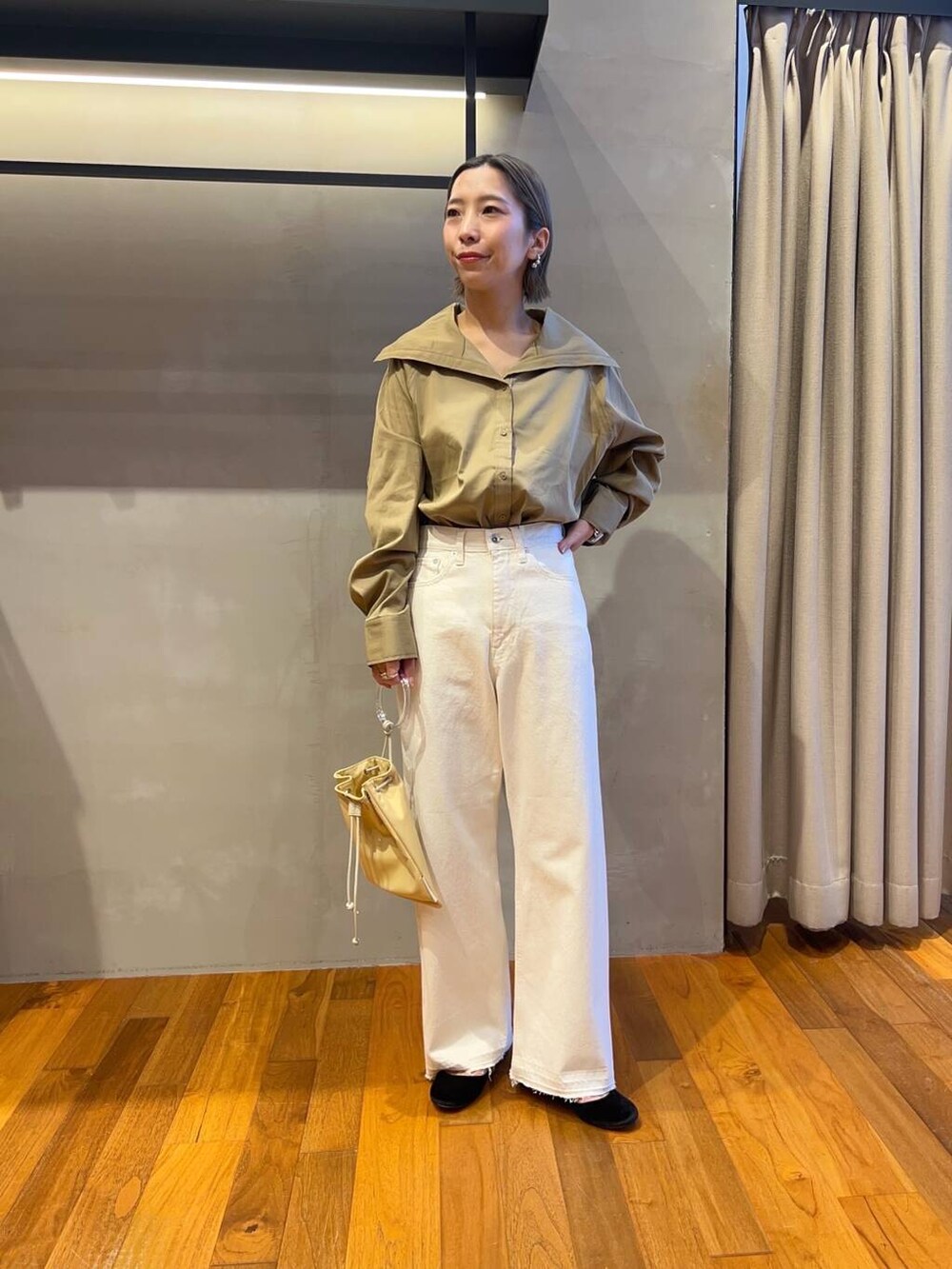 イエロー系のTシャツ/カットソー、イエロー系のショルダーバッグ、ホワイト系のデニムパンツを着用したレディースの秋コーディネートの2枚目の写真