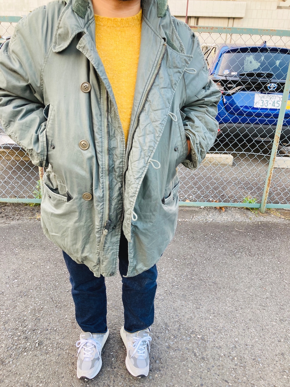 グレー系のスニーカー、ブルー系のデニムパンツ、イエロー系のニット/セーターを着用したメンズの秋コーディネートの2枚目の写真