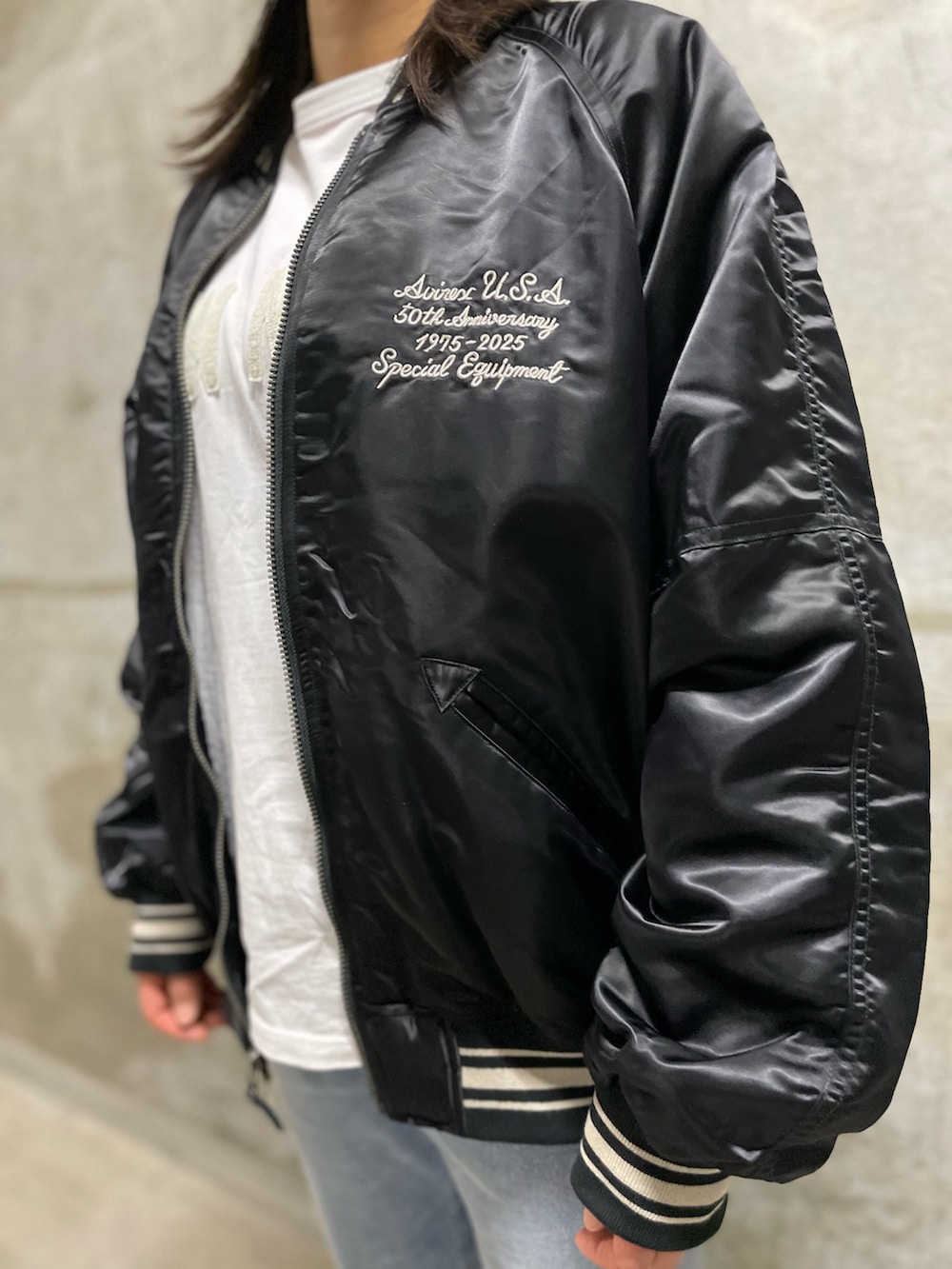 ホワイト系のTシャツ/カットソー、ブラック系のスタジャン、ブルー系のデニムパンツを着用したレディースの秋コーディネートの4枚目の写真